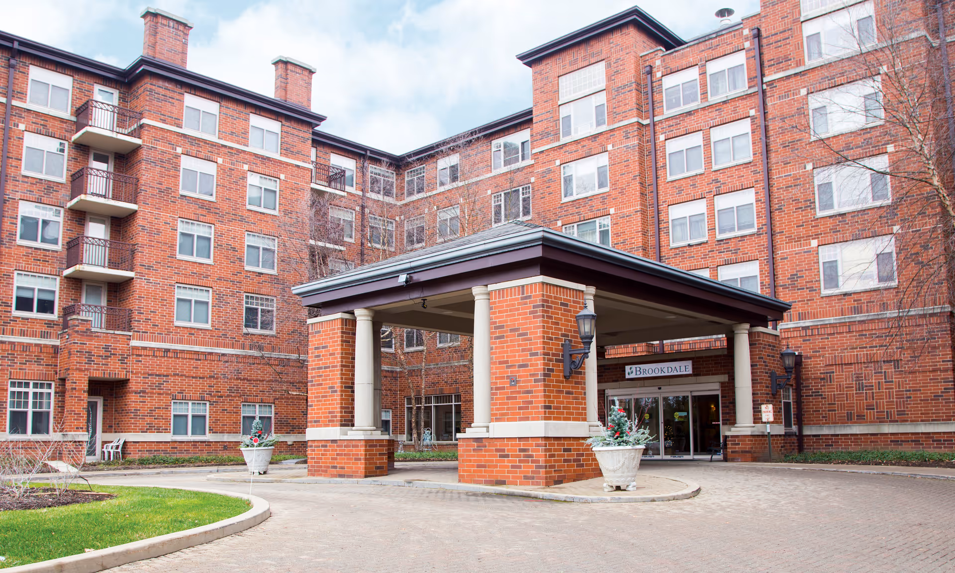 Front entrance of a brick multi-story building with a covered porte-cochère and a 'Brookdale' sign above the doors.